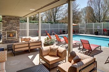 a patio with chairs and a pool and a fireplace at 2000 Lake Washington Apartments, Renton, 98056